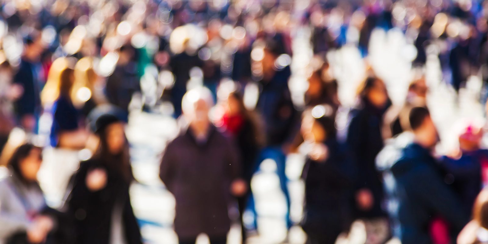 Defocused crowd of people walking along a sunny city street
